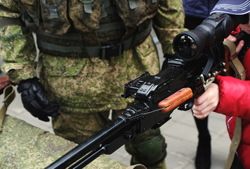 Fototapeta premium The Russian soldier and the boy with a sniper rifle at a street patriotic exhibition in the Russian Buryatia