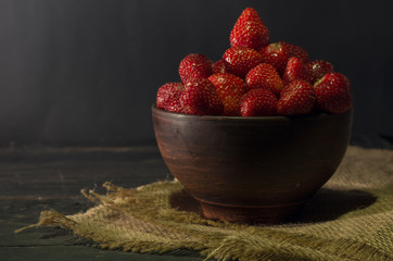 Strawberries in pottery. Clay plate and burlap.