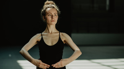 Portrait of young beautiful strong and self confident female feminist with serious face on the dark...