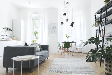 Stylish scandinavian open space with dining and living room with design map, sofa and family table....