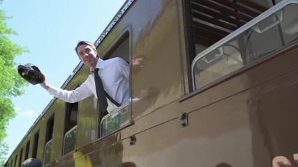 4K man with white shirt waving goodbye with hat from train window