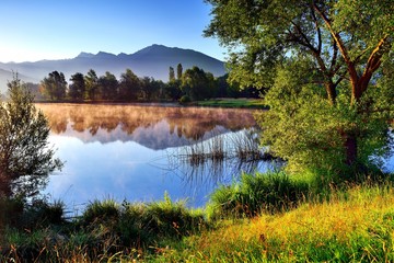 Berge im Morgenlicht spiegeln sich in einem Teich