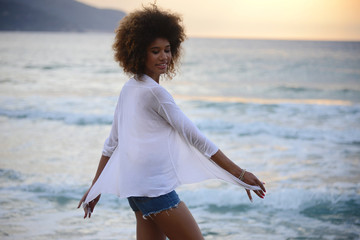 Fototapeta na wymiar beautiful woman with afro hair having fun at sunset on the sea
