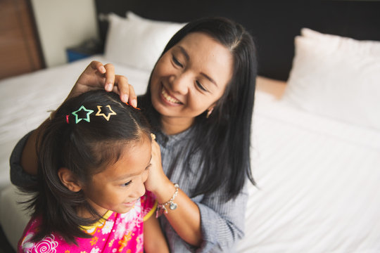 Asian Mother Doing Hair Of Daughter