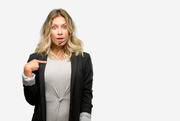 Young woman operator from call center happy and surprised cheering expressing wow gesture, pointing with finger