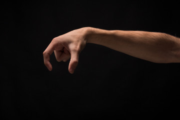 Male hand picking up something, cutout on black