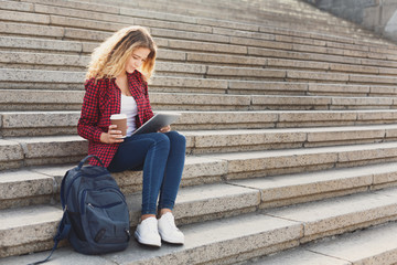 Fototapeta premium Female student working on a laptop and drinking coffee outside