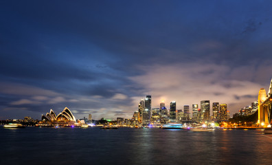 Fototapeta na wymiar Panoramic image of Sydney, Australia with Harbour Bridge during twilight blue hour.