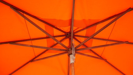 Close up below fabric orange umbrella.