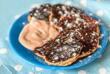 Pancakes with cinnamon and yogurt on blue plate.