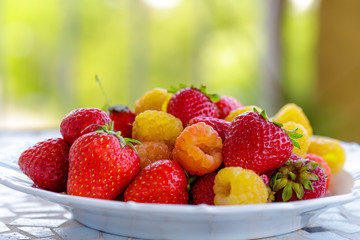 bio yellow raspberries with red strawberries on the table in the summer. close up