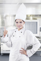 Female chef showing thumb up in the kitchen