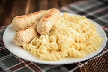 Diet healthy homemade grilled chicken sausage with pasta and cheese on dark wooden background. Healthy food for dinner.