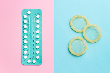 Contraceptive pills and condoms on colored background. View from above. Concept of birth control