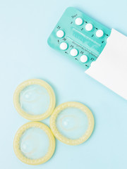 Contraceptive pills and condoms on blue background. Concept of birth control