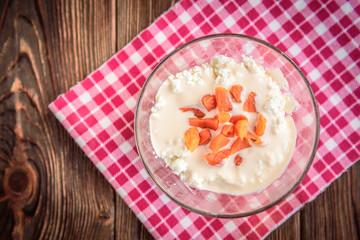 Cottage cheese with yogurt and dried apricot on dark wooden background.