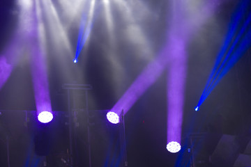 Fototapeta na wymiar Soffits during concert, robots letting blue rays on a professional dark scene