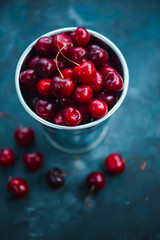 Cherries with a small metal bucket on a grey concrete background, summer berries concept with copy space. Neutral color tones still life