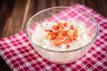 Cottage cheese with yogurt and dried apricot on dark wooden background.