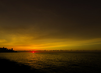 Sunset over Malecon and Atlantic Ocean with residential building in background - Havana, Cuba 
