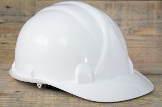 Construction safety hardhat helmet. Wooden background. Close-up