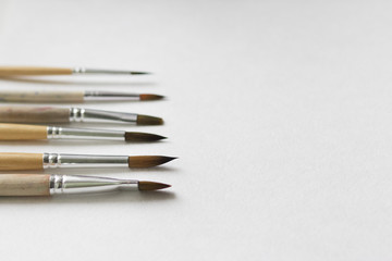 Several paintbrushes on a white paper background.