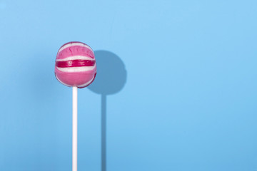 Pink Lolipop candy with shadow on pastel blue background