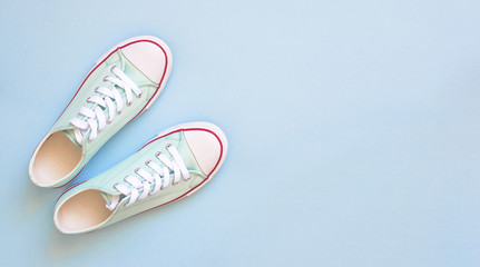 Pastel turquoise female sneakers on blue background. Flat lay, top view minimal background. Fashion blog or magazine concept.