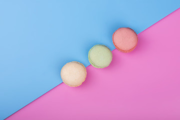 Colorful macaroons on pink blue background. Flat lay