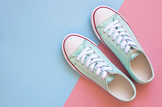 Pastel turquoise female sneakers on blue and pink background. Flat lay, top view minimal background. Fashion blog or magazine concept.