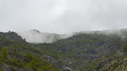 Fototapeta na wymiar Peak mountains are surrounded by low clouds