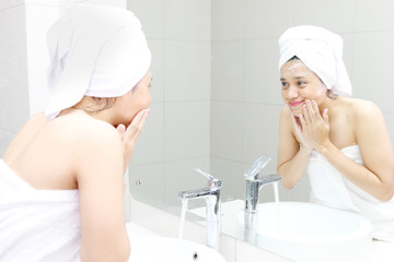 Young woman cleansing her face in the bathroom