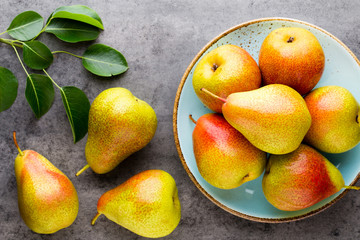 Fresh bio pear with leaves on the plate. Gray stone table.