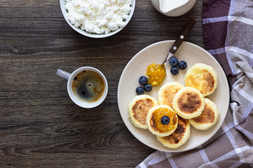 Cottage cheese pancakes (syrniki) with sour cream, orange jam and fresh blueberries on a plate. Breakfast or lunch concept. 