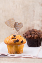 Homemade chocolate muffins with heart, vintage background.