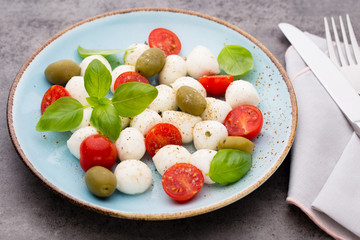 Delicious caprese salad with ripe cherry tomatoes and mini mozzarella cheese balls with fresh basil leaves.