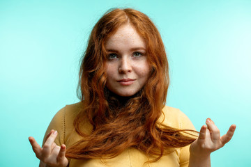 Beautiful calm young redhead female with hair tied crossed around her neck holding hands in mudra...
