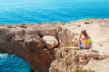 One caucasian girl sitting on the edge of the cliff