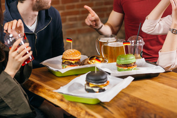Black and green bun Burgers in selective focus. A happy group of young heterosextual people are enjoying their delicious and tasty burgers in the burger-bar.