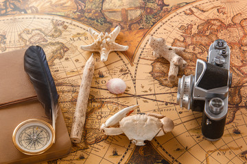 Seashells, brass compass, wooden pencil, old camera lie on vintage card