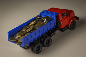 Many different coins in a toy truck on a table