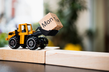 Miniature tracktor lift up Monday wooden block using as business and industry concept