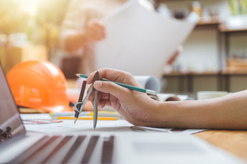 Hands of architect or engineer using drawing compass with blueprint on desk in office.Team of architects engineer discussing and check documents and business workflow.Construction concept.