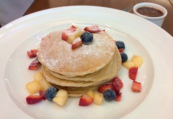 pile of pancakes with icing sugar and fresh fruits
