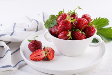 Fresh red strawberry in a bowl with green leaf on white background