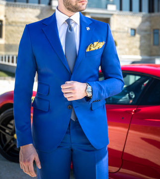 Man In Expensive Custom Tailored Suit Posing In Front Of Expensive Car Outdoors