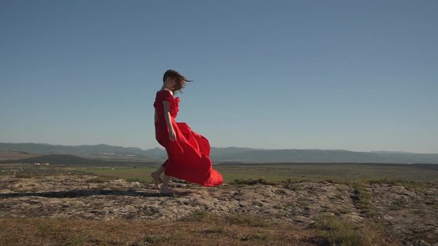 woman model in scarlet fluttering in the wind dress and barefoot