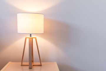 Modern bedroom lamp lit against white wall with copy space - obrazy, fototapety, plakaty