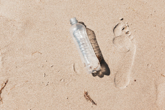 Ecological foot print symbol image with plastic waste on ocean beach
