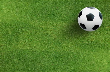 Soccer football ball on green grass of soccer field background.